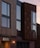 A modern building facade featuring large reflective windows and a mix of materials, including wood paneling and rust-colored metal cladding. A warmly lit entrance is visible, and there is a sign with the word 'KENNAWAY' above the door. The sky is clear with a subtle gradient of colors indicating a sunset or sunrise.