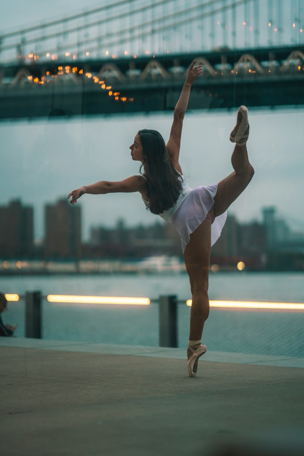 Ballerina steht tagsüber auf einem Fuß auf Zehenspitzen an der Stadtbucht