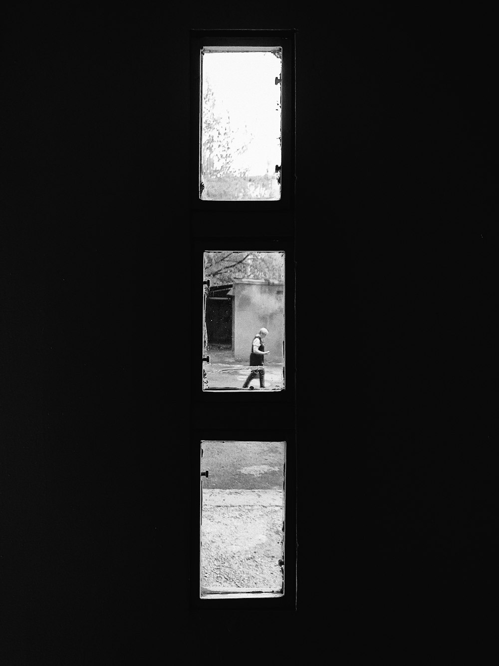 a black and white photo of a person sitting in a window