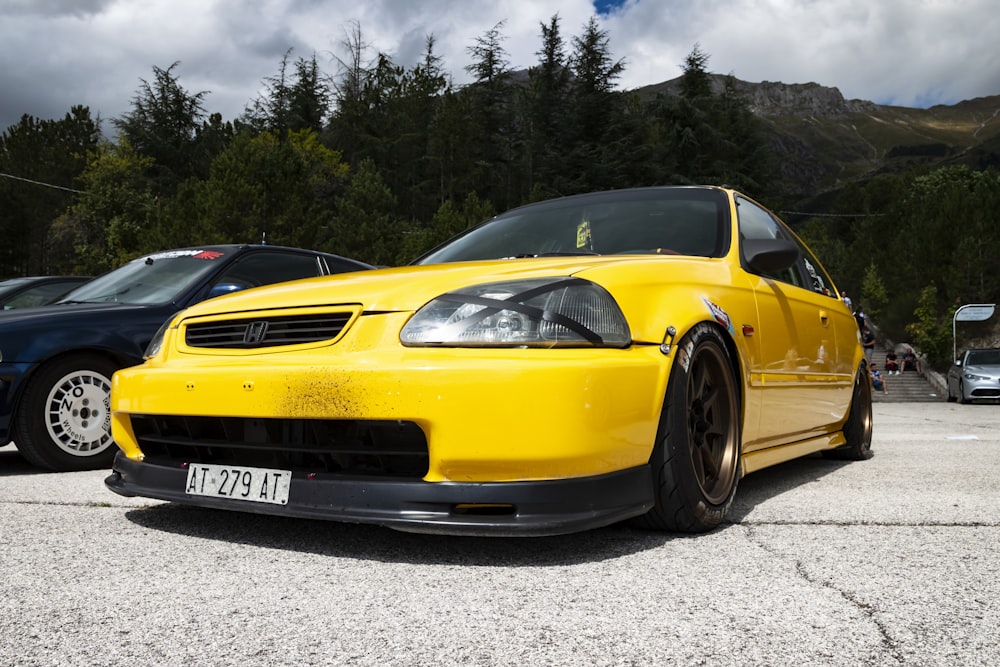 coupé Honda jaune garé à côté des voitures