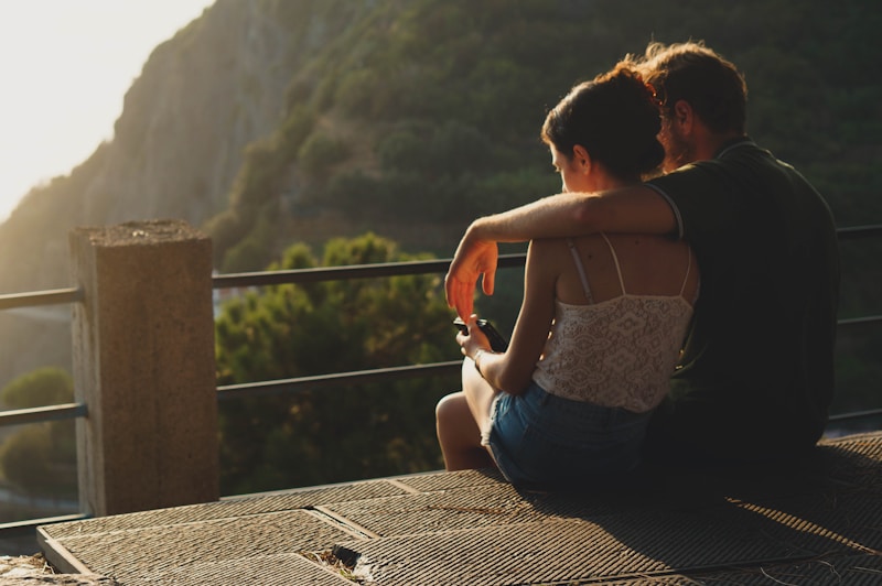 man and woman sitting on concrete surface
