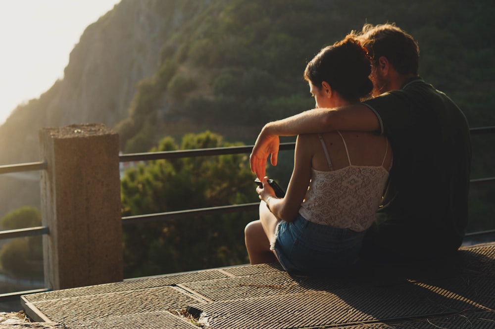 man and woman sitting on concrete surface