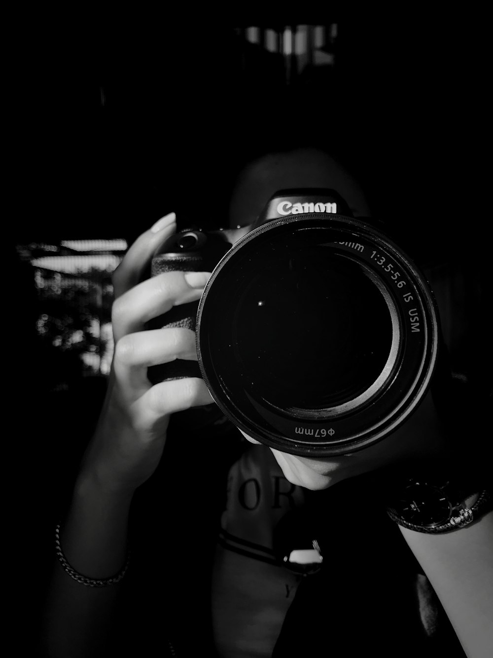 grayscale photo of person holding Canon DSLR
