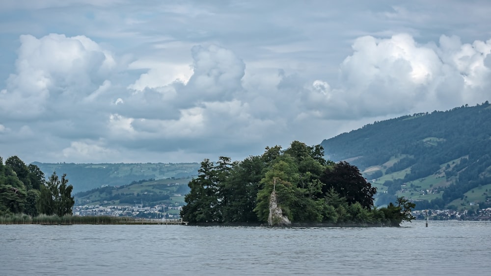 body of water viewing mountain under white and blue skies during daytime