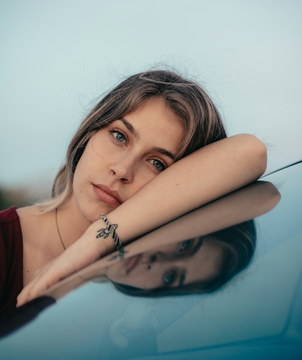 woman wearing red top leaning on glass