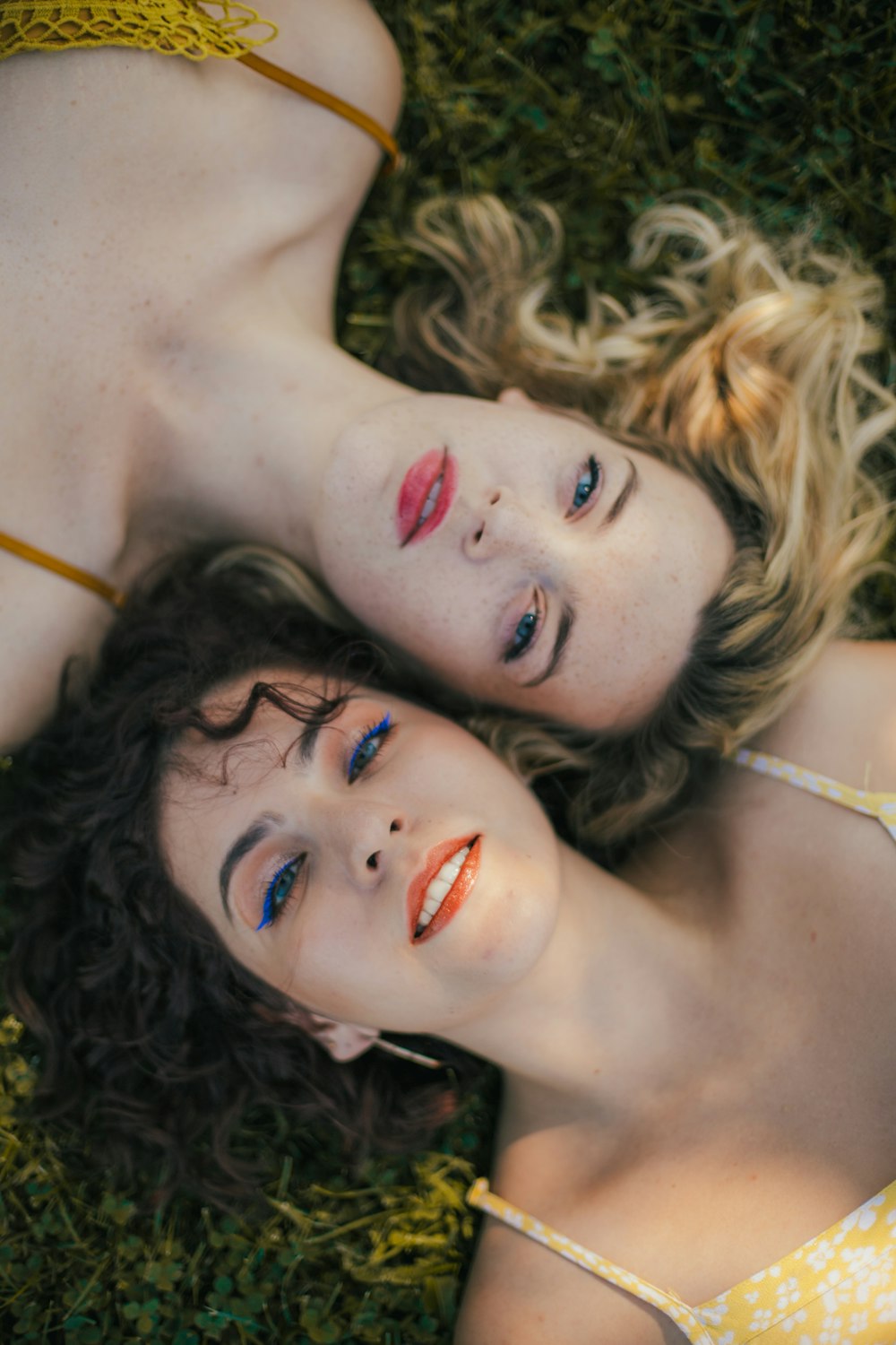 2 women wearing yellow string strap top lying on grassland