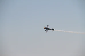 A sleek aerobatic plane twisting sharply against a clear blue sky.
