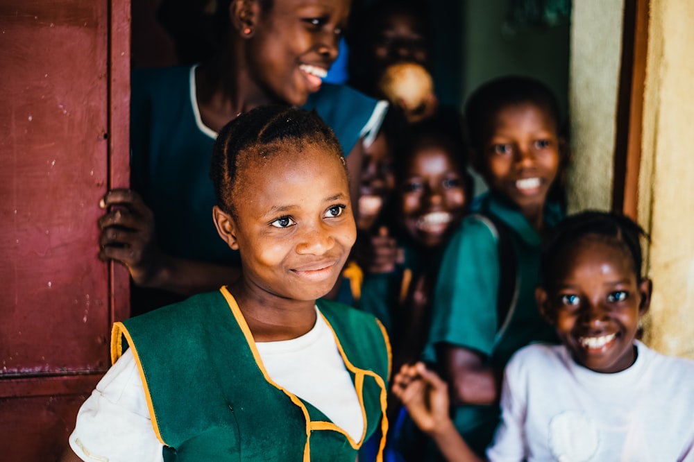 children smiling while standing near open door