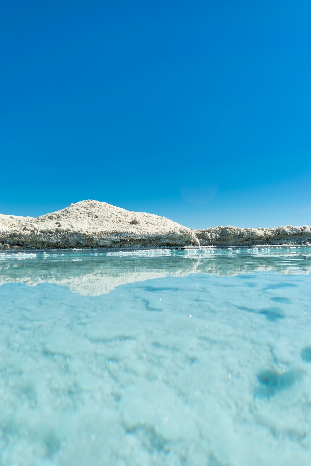 clear water near mountain during daytime