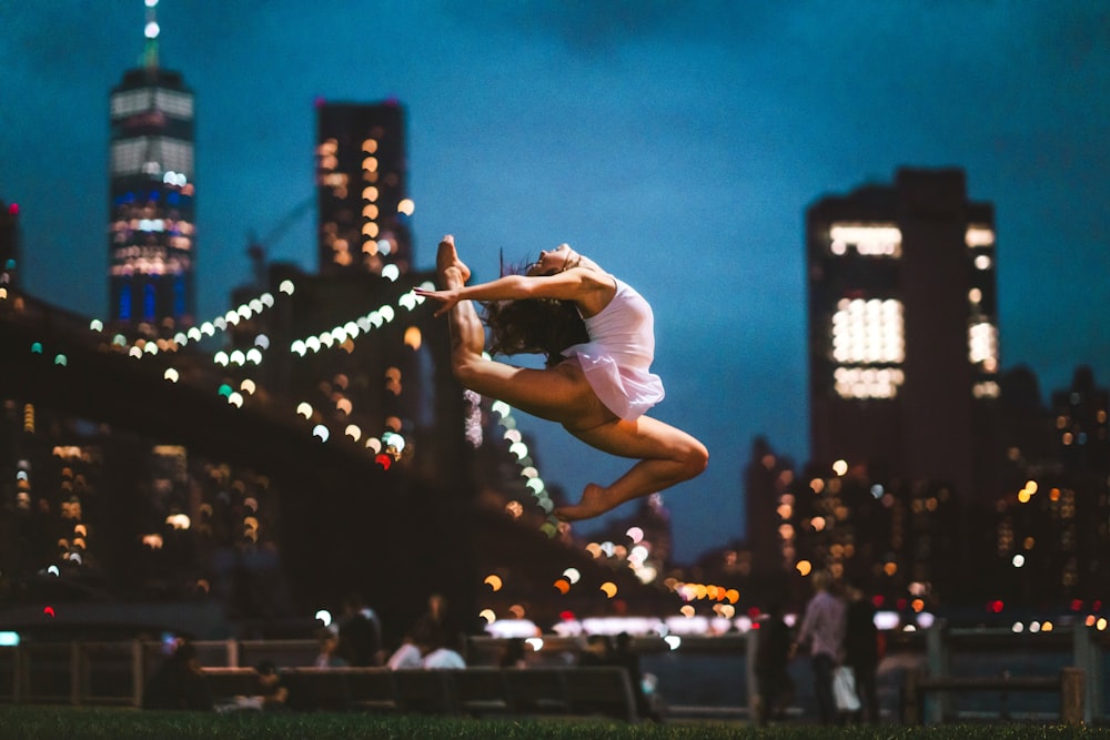 selective focus photography ballerina doing stunt near bridge