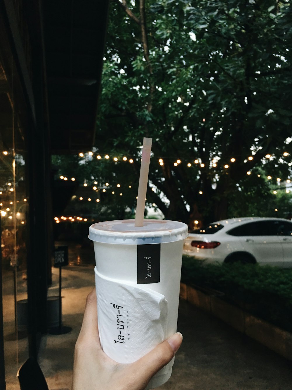 person hold a paper cup with lid and straw