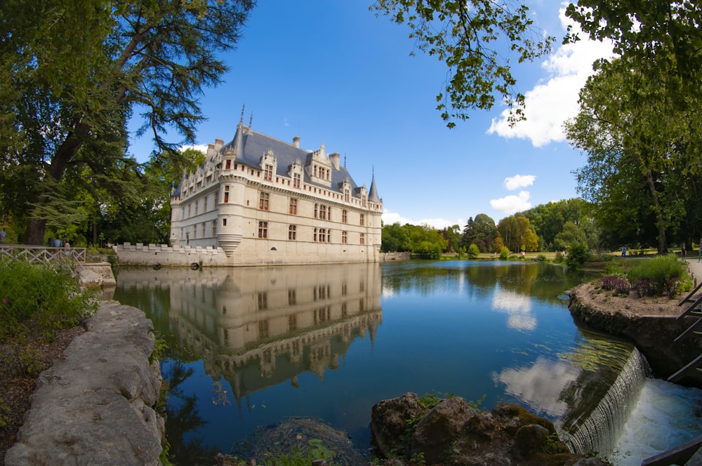 Château blanc au toit bleu entouré d’eau pendant la journée