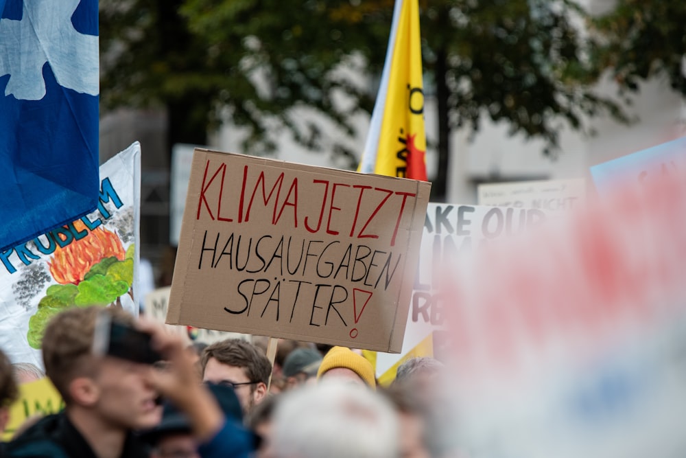 person holding a banner with Kilma jetzt hausaugaben spater!