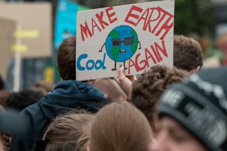 A bold, colorful illustration of a protest sign that reads 'Make Satire Great Again' held by a crowd.