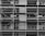 A black and white image of a building under construction featuring multiple levels of scaffolding and partially built balconies. The structure is predominantly concrete with visible metal framework for support.