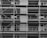 A black and white image of a building under construction featuring multiple levels of scaffolding and partially built balconies. The structure is predominantly concrete with visible metal framework for support.
