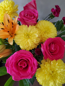 A vibrant birthday floral arrangement with bright pink and yellow flowers in a modern vase.