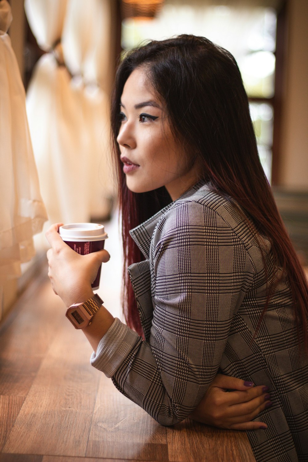 woman wearing gray and black plaid coat holding disposable cup