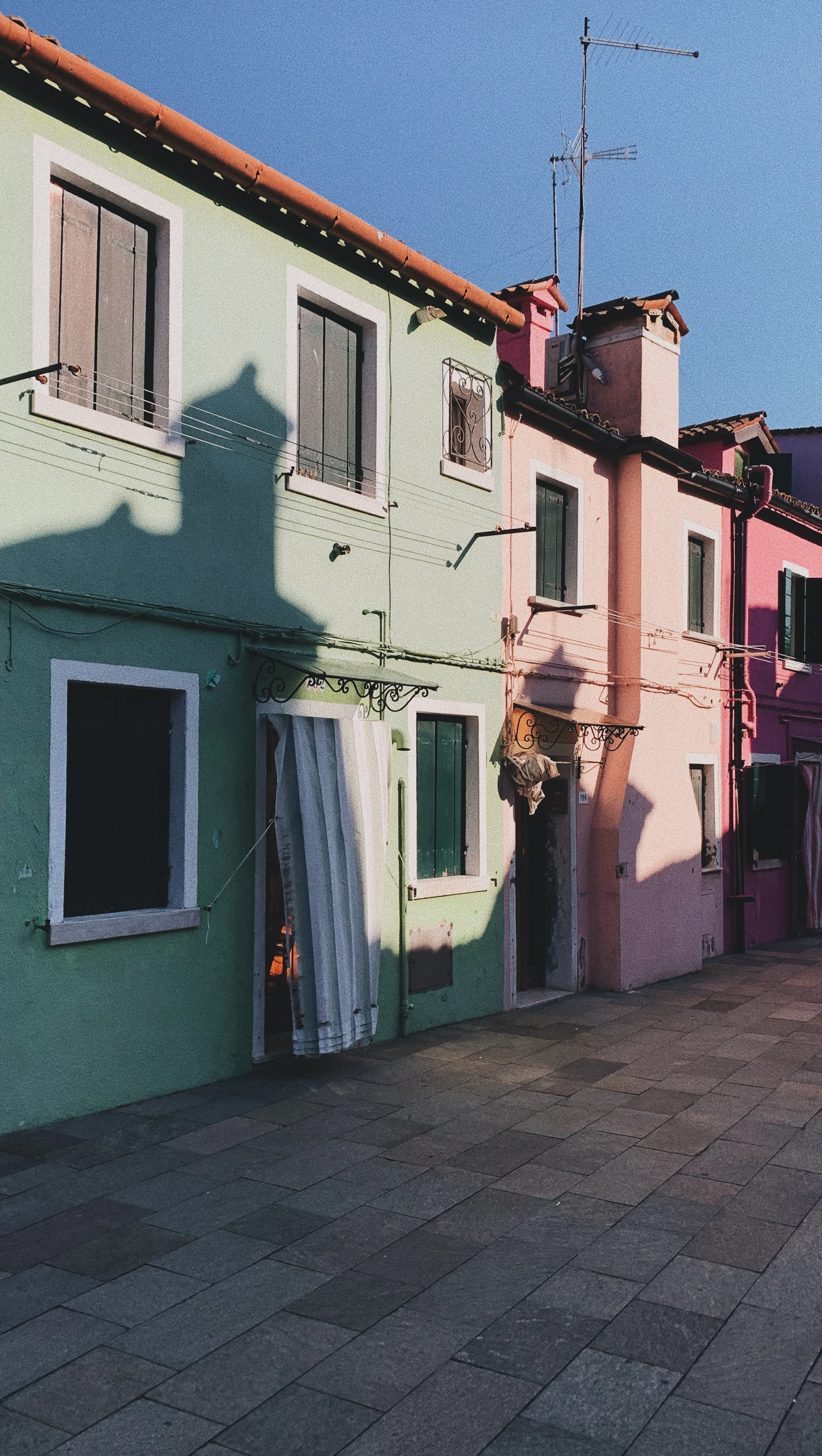 Colorful houses lining the steep streets of Porto, bathed in soft morning light with a purple tint.