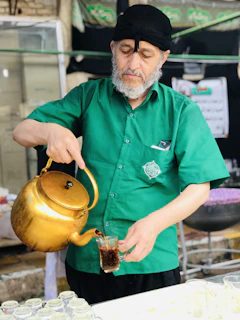 Close-up of a helper and an elderly man sharing a joyful moment over a cup of tea at a kitchen table.