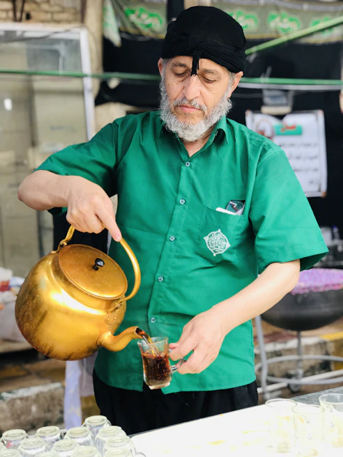 Close-up of a helper and an elderly man sharing a joyful moment over a cup of tea at a kitchen table.