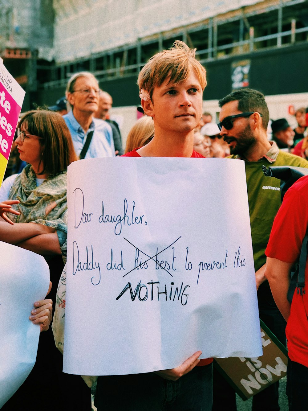 man holding banner with text overlay during daytime