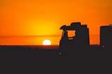 Twilight shot of a truck silhouetted against a glowing orange sunset sky.