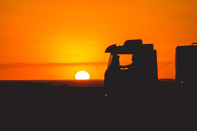 Twilight shot of a truck silhouetted against a glowing orange sunset sky.