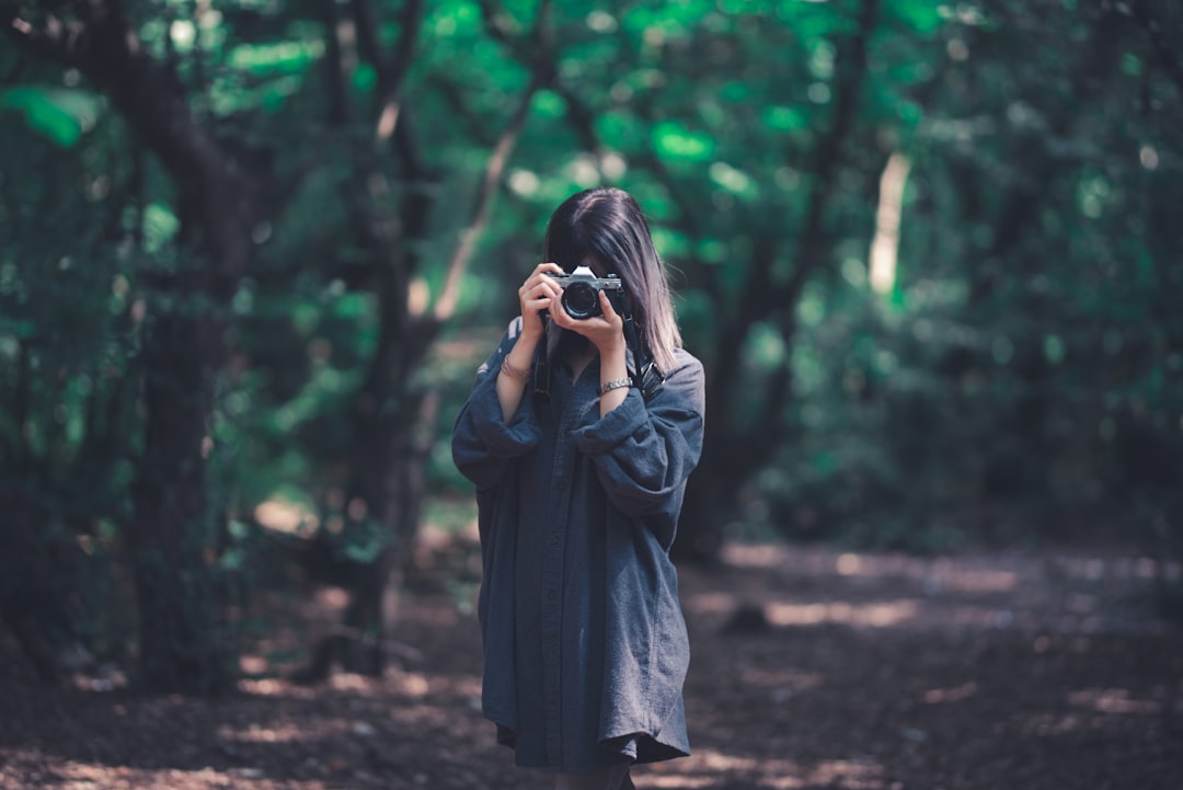 woman using camera near trees