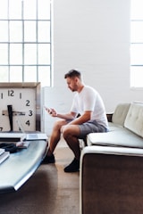 sitting man wearing white t-shirt using smartphone