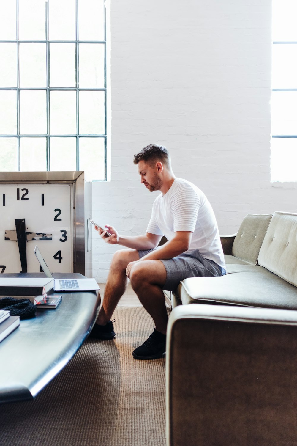 Hombre sentado con camiseta blanca usando un teléfono inteligente