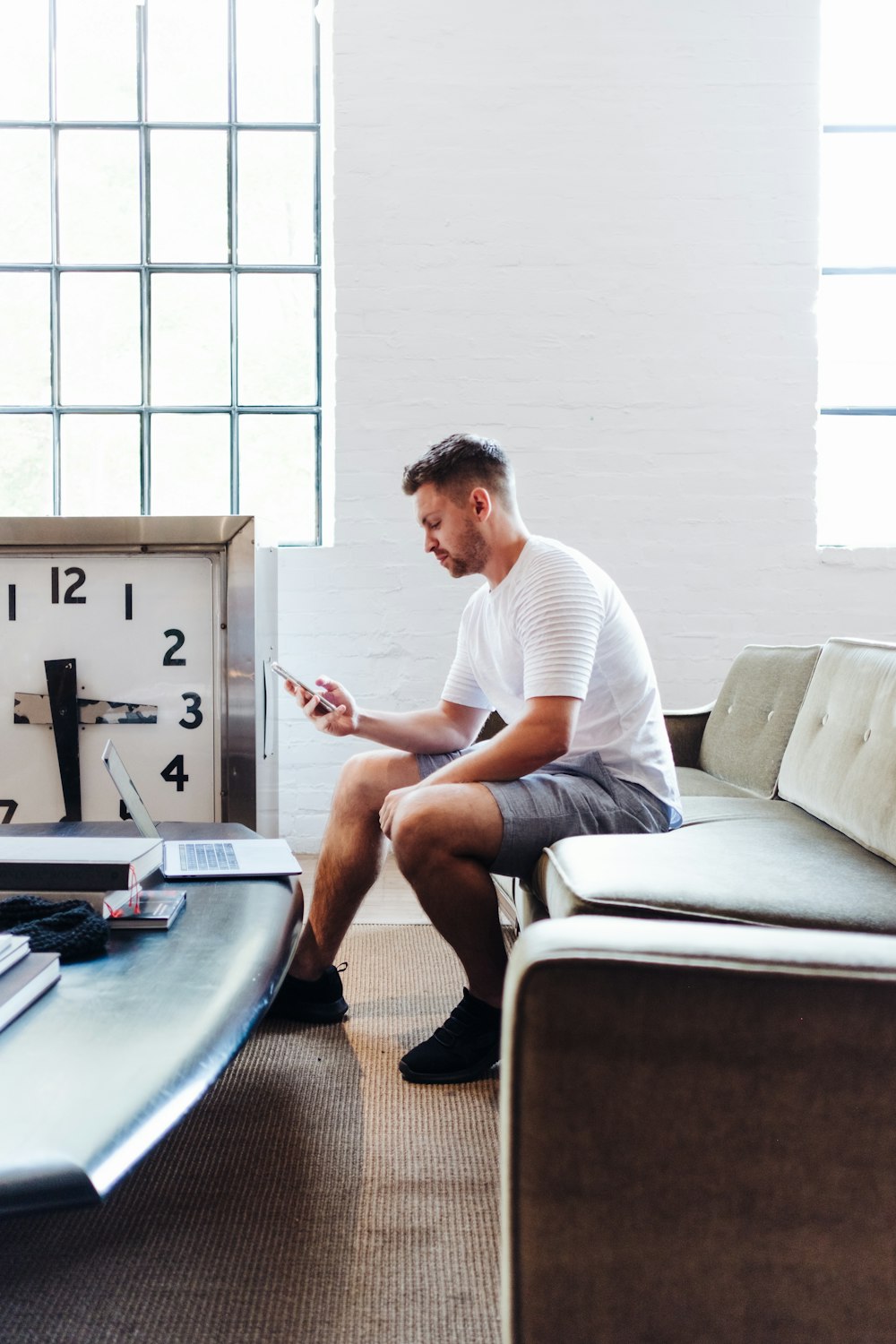 sitzender Mann trägt weißes T-Shirt mit Smartphone