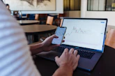 person using smartphone and MacBook Pro