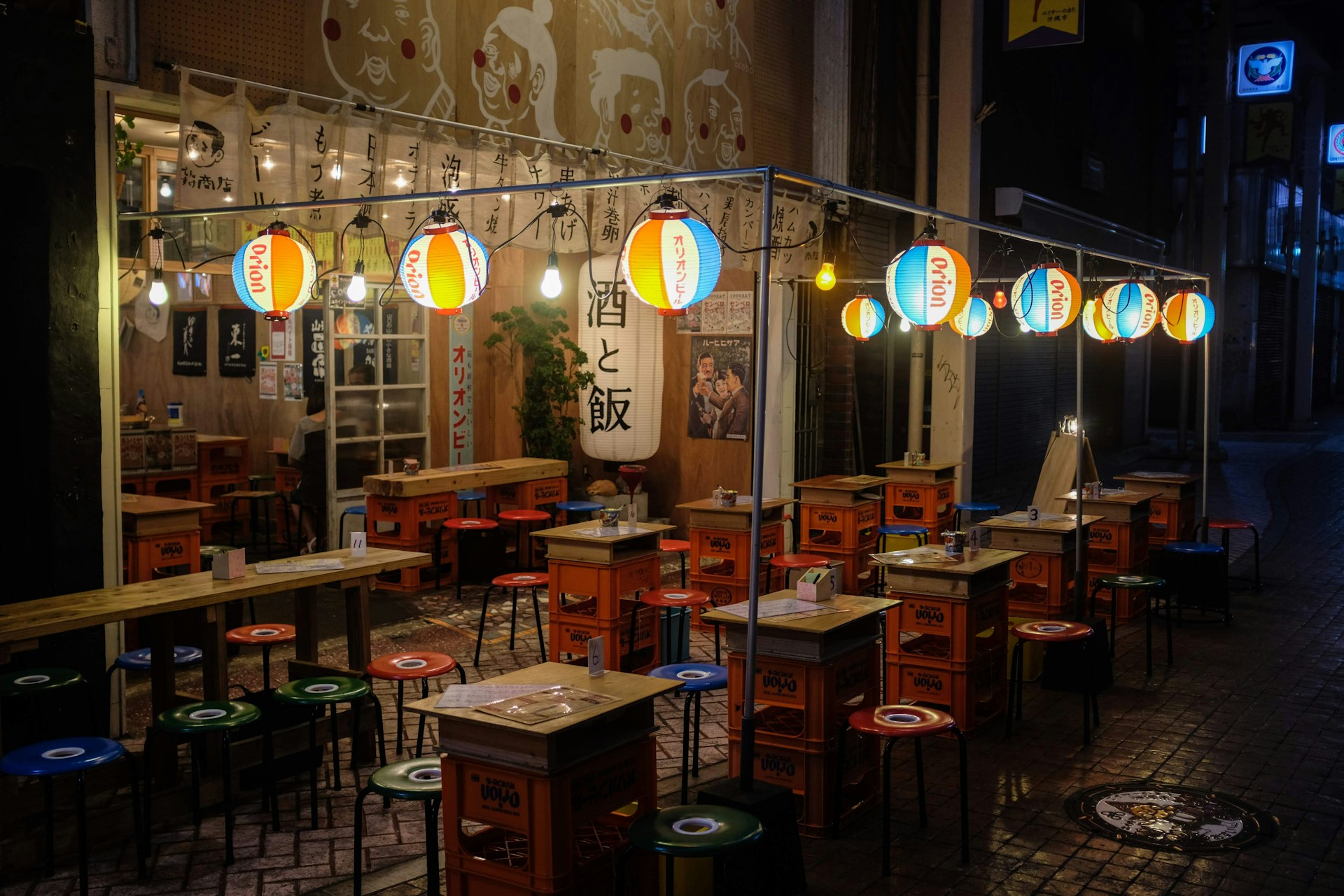 A bustling street-food style setup with colorful paper lanterns and a friendly chef preparing fresh Japanese street food.
