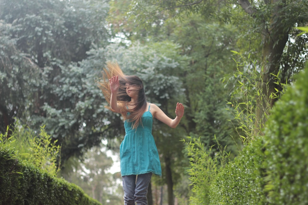 a young girl is playing with her hair in the park