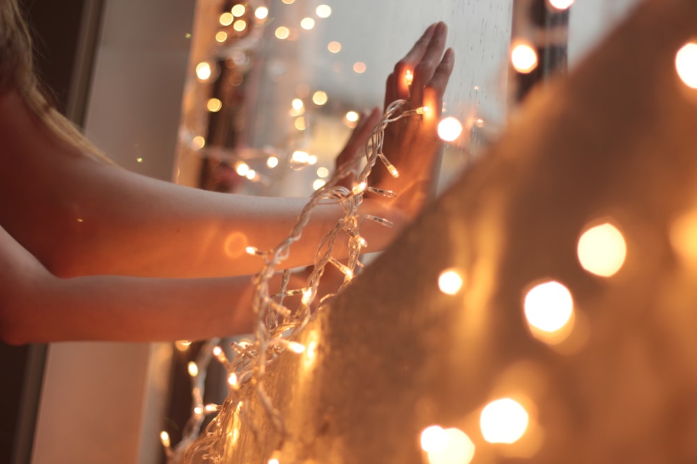 a woman standing in front of a mirror holding a string of lights