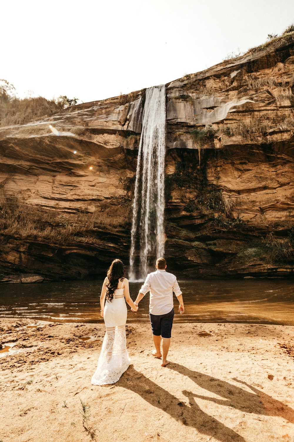 man and woman walking towards waterfalls