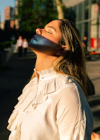 A smiling woman outdoors, basking in sunlight with a peaceful expression