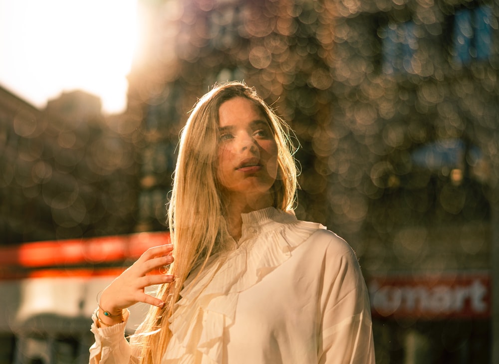 woman wearing white long-sleeved blouse glancing her left side while standing