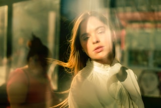 Softly lit photo of a woman journaling by a sunlit window, embodying calm reflection.