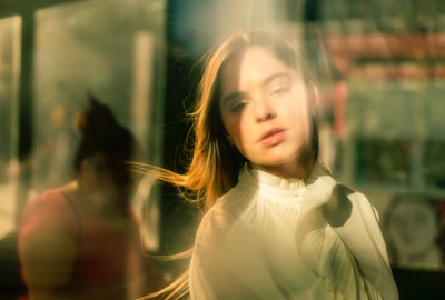 Softly lit photo of a woman journaling by a sunlit window, embodying calm reflection.