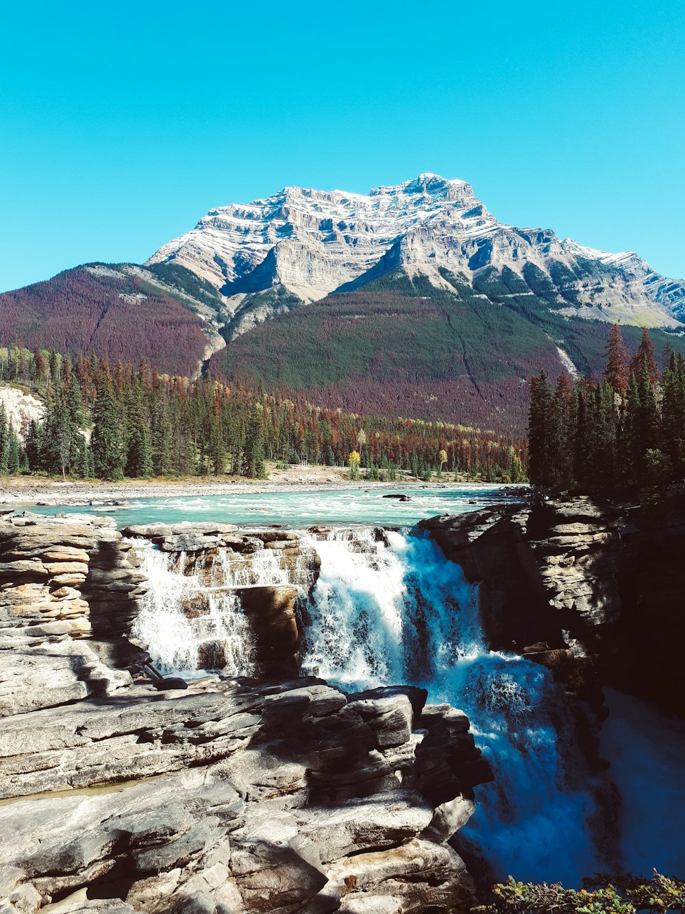 waterfalls cascading near mountain during daytime