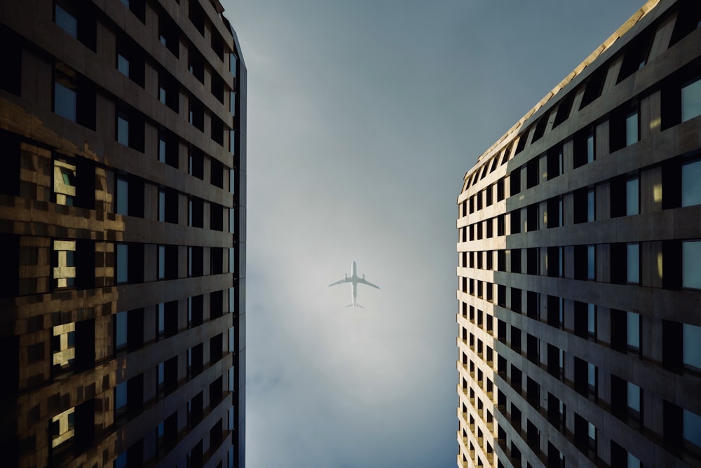 Photographie en contre-plongée d’immeubles de grande hauteur montrant un avion blanc