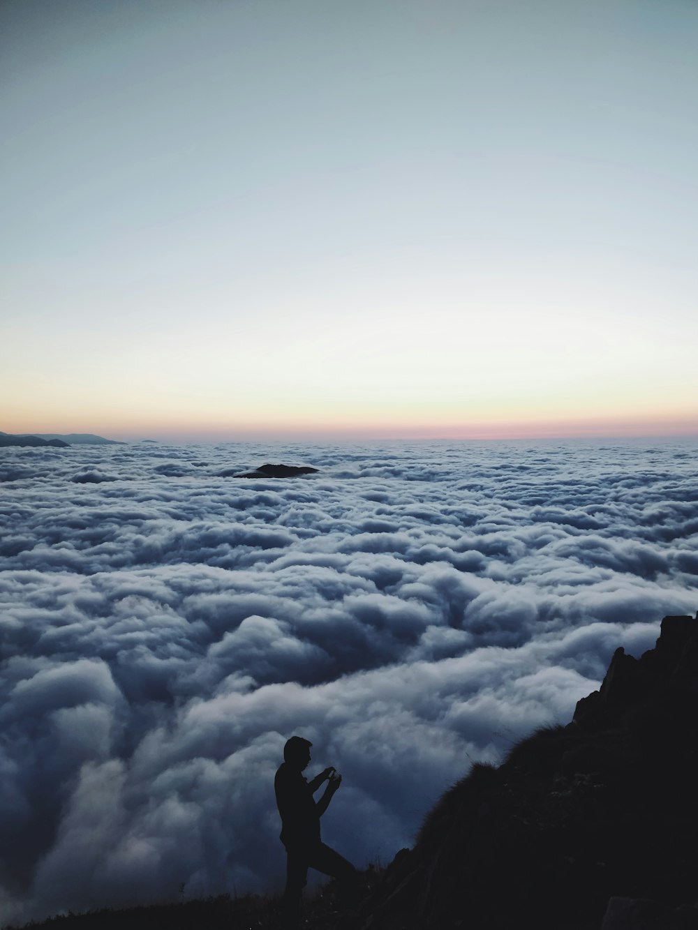 person standing on top of mountain with clouds