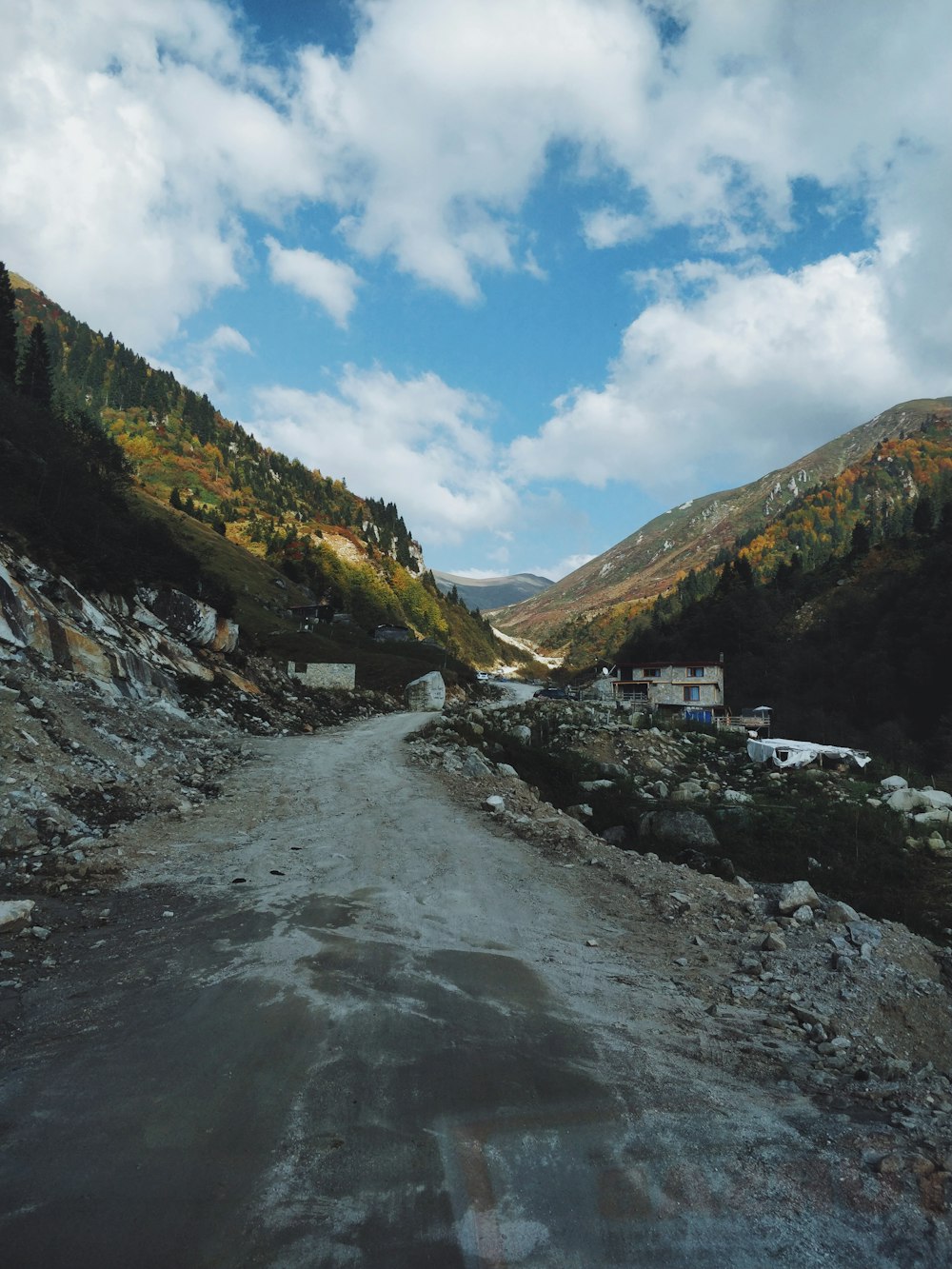 a dirt road surrounded by mountains under a cloudy sky