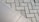 The image displays two different types of surfaces divided diagonally. The left side shows a smooth, possibly ceramic or concrete tile surface. The right side features a pattern of interlocking grey concrete bricks with a herringbone layout.