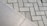 The image displays two different types of surfaces divided diagonally. The left side shows a smooth, possibly ceramic or concrete tile surface. The right side features a pattern of interlocking grey concrete bricks with a herringbone layout.