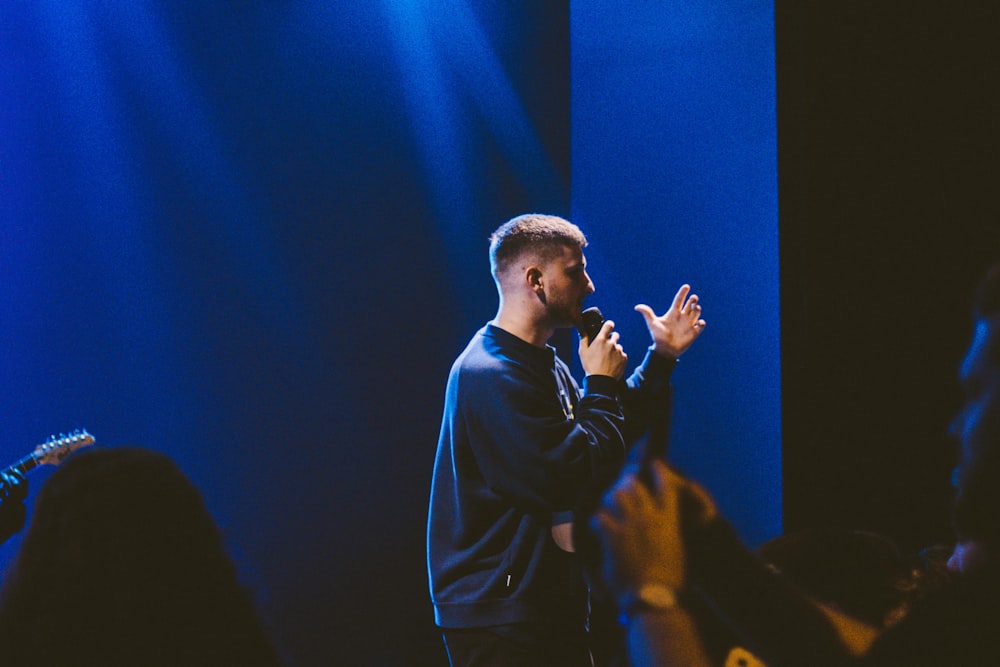 man wearing blue sweater holding microphone