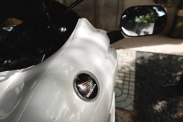 Close-up of a shiny Honda with a 'Sold' sign in front, under bright Miami sun.