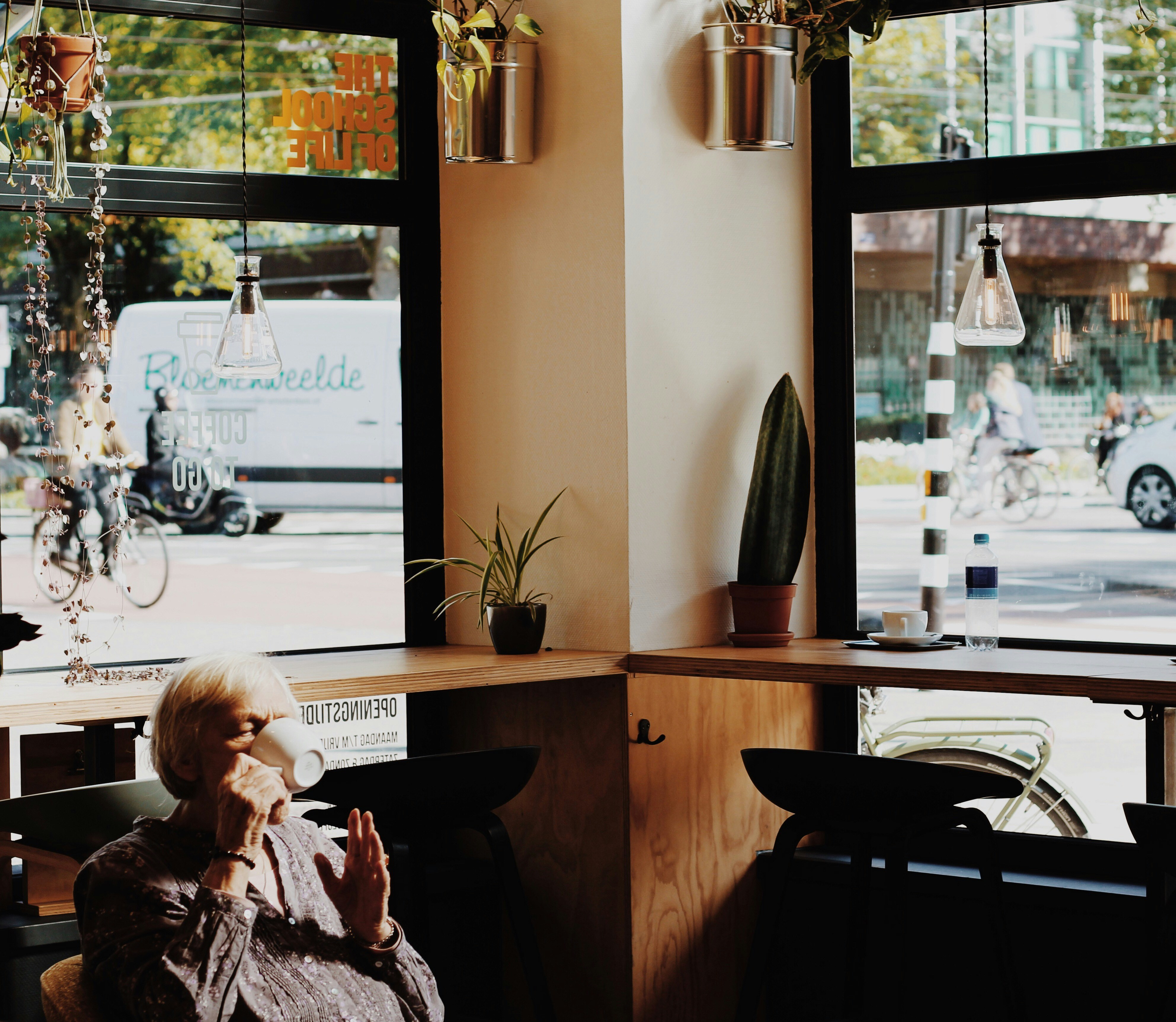 Image of a person enjoying a cup of coffee by a large window overlooking a vibrant neighborhood. - Apartments with large windows